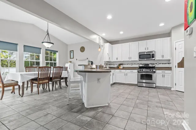 a kitchen with stainless steel appliances granite countertop a stove a sink a microwave and a dining table