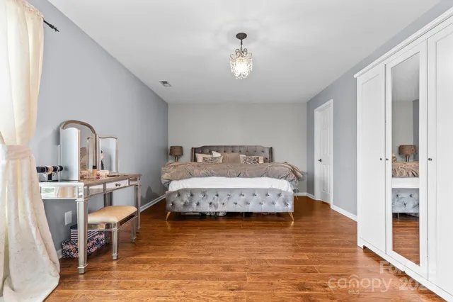 a spacious bedroom with a bed and wooden floor