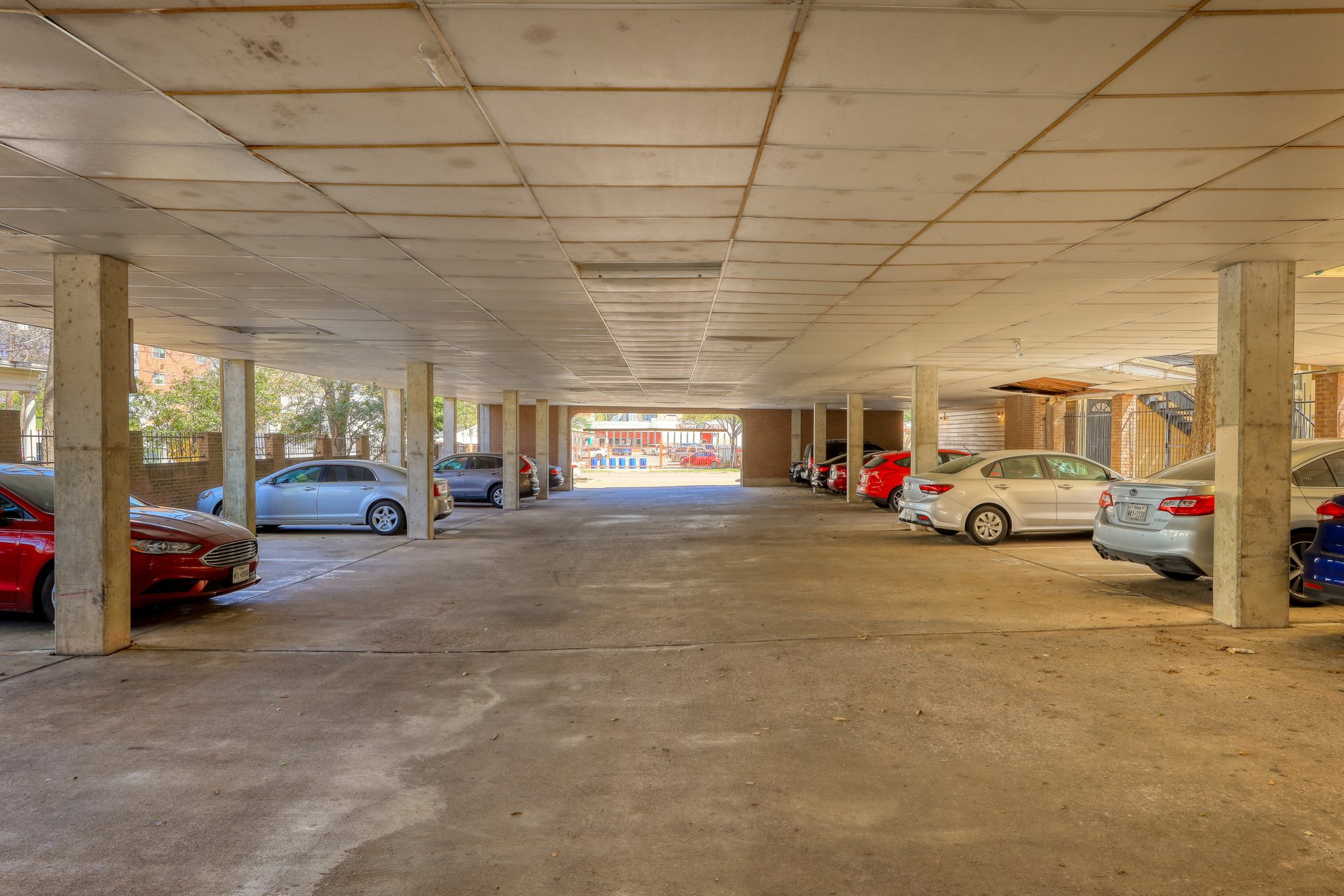 2802 Nueces Street, Unit 306 Austin, TX 78705 - Photo 18 of 20 Covered parking area with concrete flooring, support columns, and overhead paneling