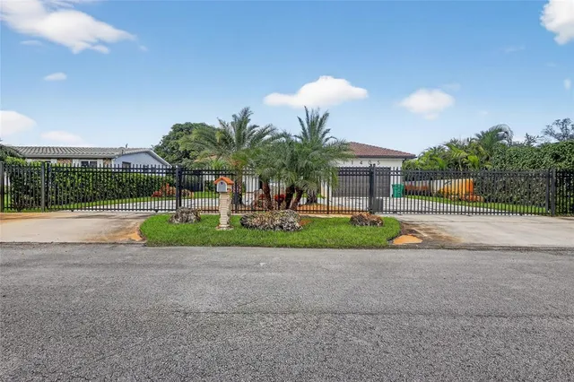 a view of house with a big yard and palm trees