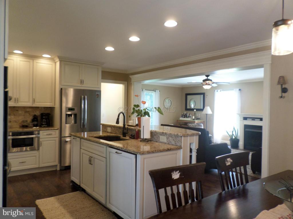 9018 Bethel Road Willards, MD 21874 - Photo 9 of 42 a kitchen with kitchen island granite countertop a stove a sink a refrigerator with a dining table and chairs