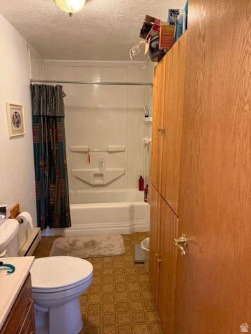 1043 East 4000th Street South Vernal, UT 84078 - Photo 19 of 31 Bathroom featuring wood-finish cabinetry, a white bathtub with integrated shower, and patterned floor tiling