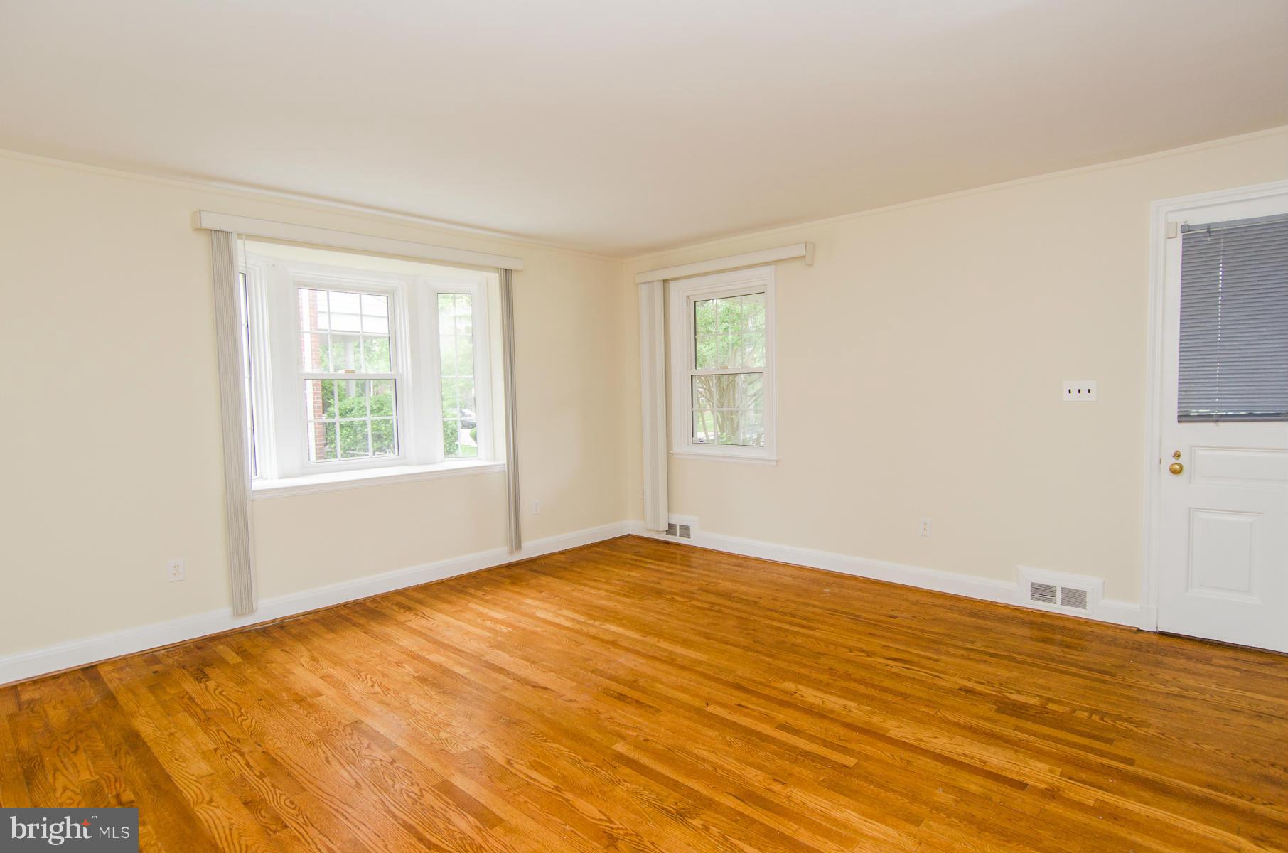1417 Stonewood Road Baltimore, MD 21239 - Photo 3 of 28 a view of an empty room with wooden floor and a window