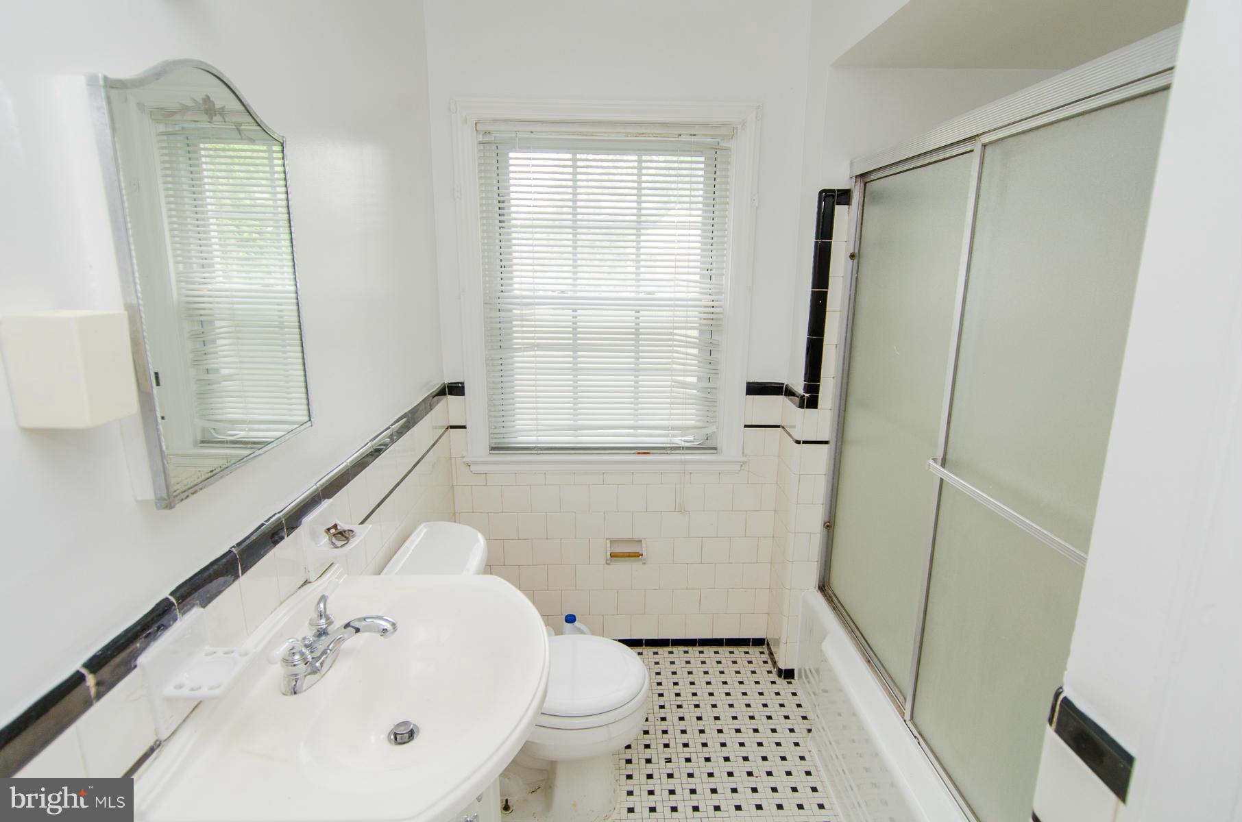 1417 Stonewood Road Baltimore, MD 21239 - Photo 10 of 28 a bathroom with a sink a toilet a shower a window and vanity