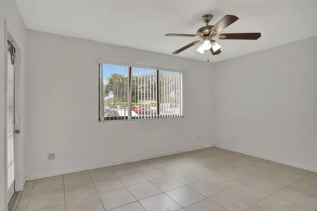 an empty room with chandelier fan and windows