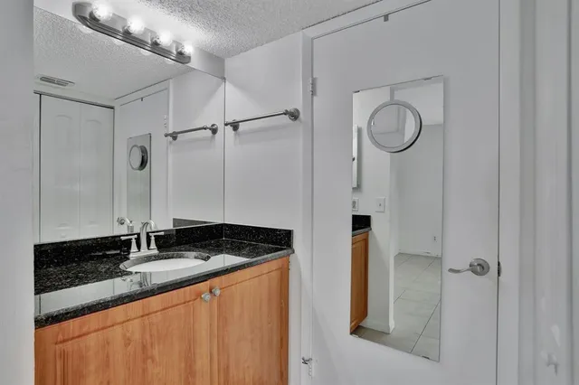 a bathroom with a granite countertop sink and a mirror