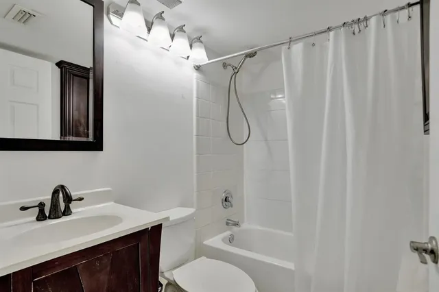 a bathroom with a sink vanity granite tub shower and a toilet
