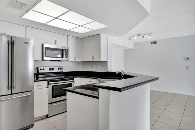 a kitchen with granite countertop a sink stove and refrigerator