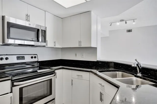 a kitchen with granite countertop white cabinets and stainless steel appliances