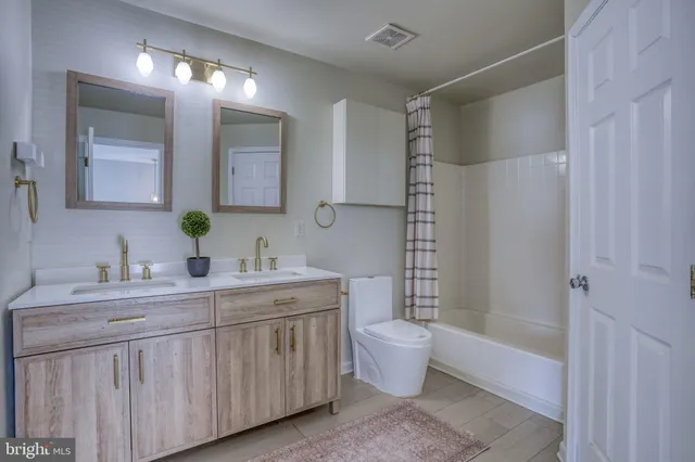 a bathroom with a double vanity sink toilet mirror and bathtub