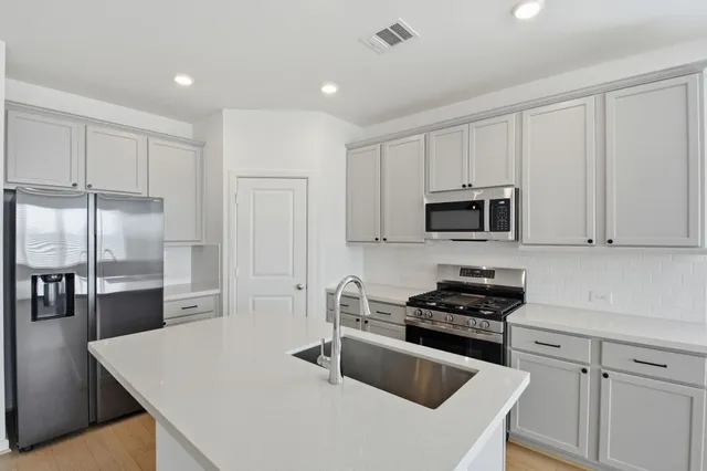 a kitchen with stainless steel appliances granite countertop white cabinets a refrigerator a sink a stove and white cabinets