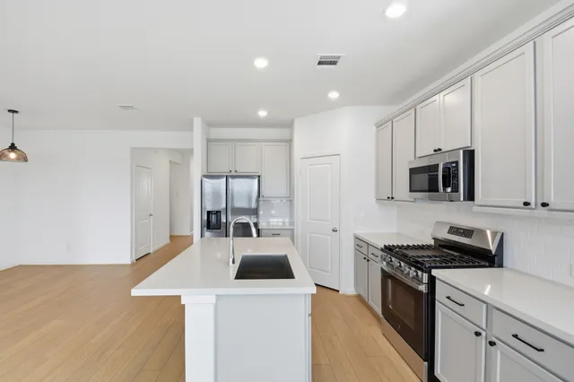 a kitchen with stainless steel appliances a stove a sink a microwave and cabinets