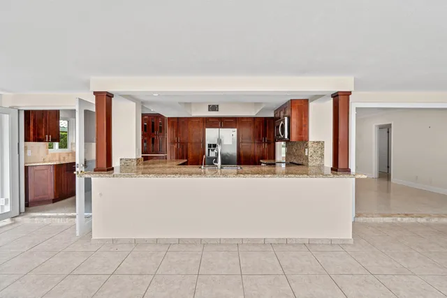 a living room with stainless steel appliances kitchen island granite countertop a refrigerator a stove and a sink