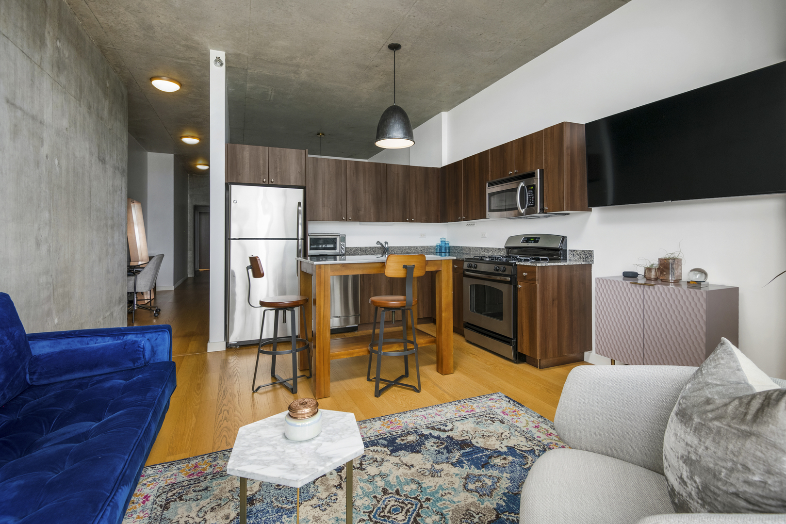 235 West Van Buren Street, Unit 2009 Chicago, IL 60607 - Photo 7 of 14 a living room with stainless steel appliances kitchen island granite countertop a couch wooden floor and a view of kitchen