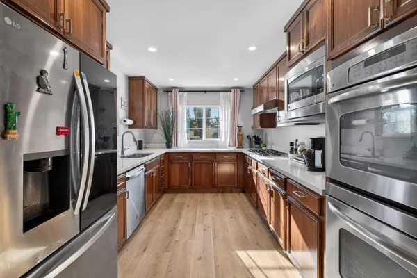 a large kitchen with stainless steel appliances granite countertop a large counter top a stove and a refrigerator