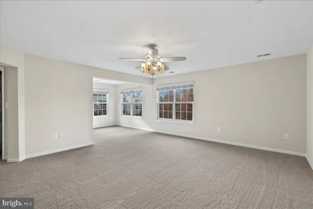 an empty room with chandelier and a kitchen
