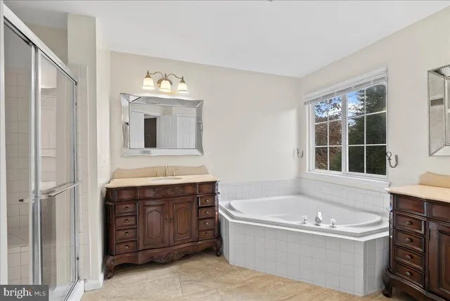 a bathroom with a tub a double vanity sink and a mirror