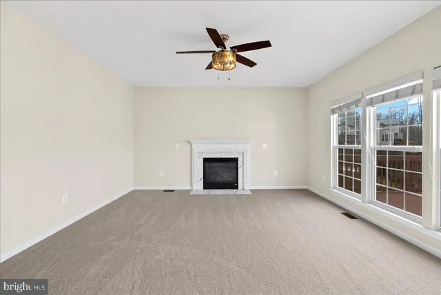 an empty room with ceiling fan and windows