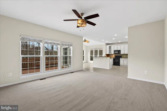 a view of a livingroom with a ceiling fan and kitchen view