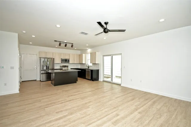 a large white kitchen with kitchen island a sink stainless steel appliances and cabinets