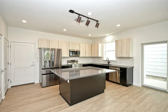 a kitchen with stainless steel appliances granite countertop a refrigerator a stove a sink and a microwave