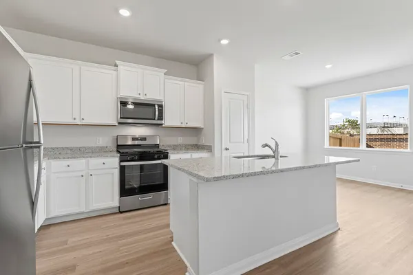 a kitchen with stainless steel appliances granite countertop a stove a sink and a refrigerator