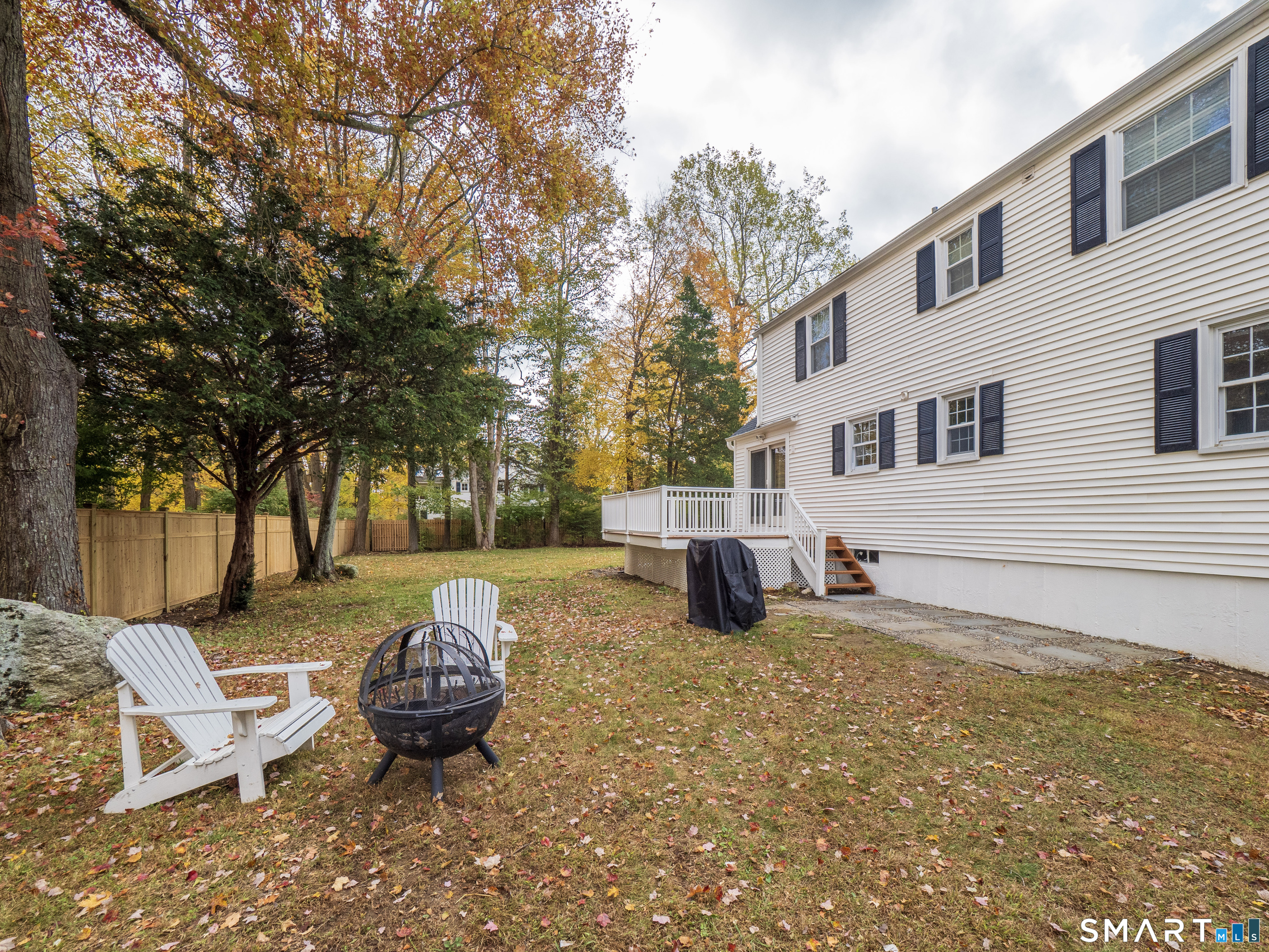 46 Crest Road Ridgefield, CT 06877 - Photo 34 of 41 a view of a backyard with table and chairs and a barbeque with potted plants and large trees