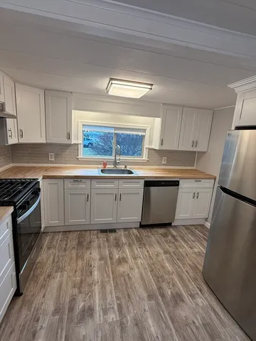 a kitchen with wooden floors appliances a sink and cabinets