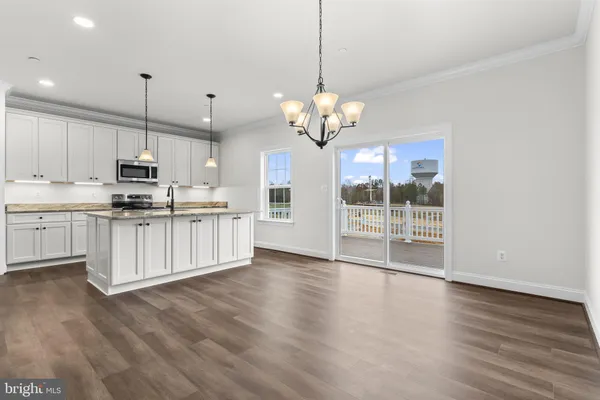 a kitchen with stainless steel appliances granite countertop a stove a sink dishwasher a microwave oven with white cabinets and a wooden floor