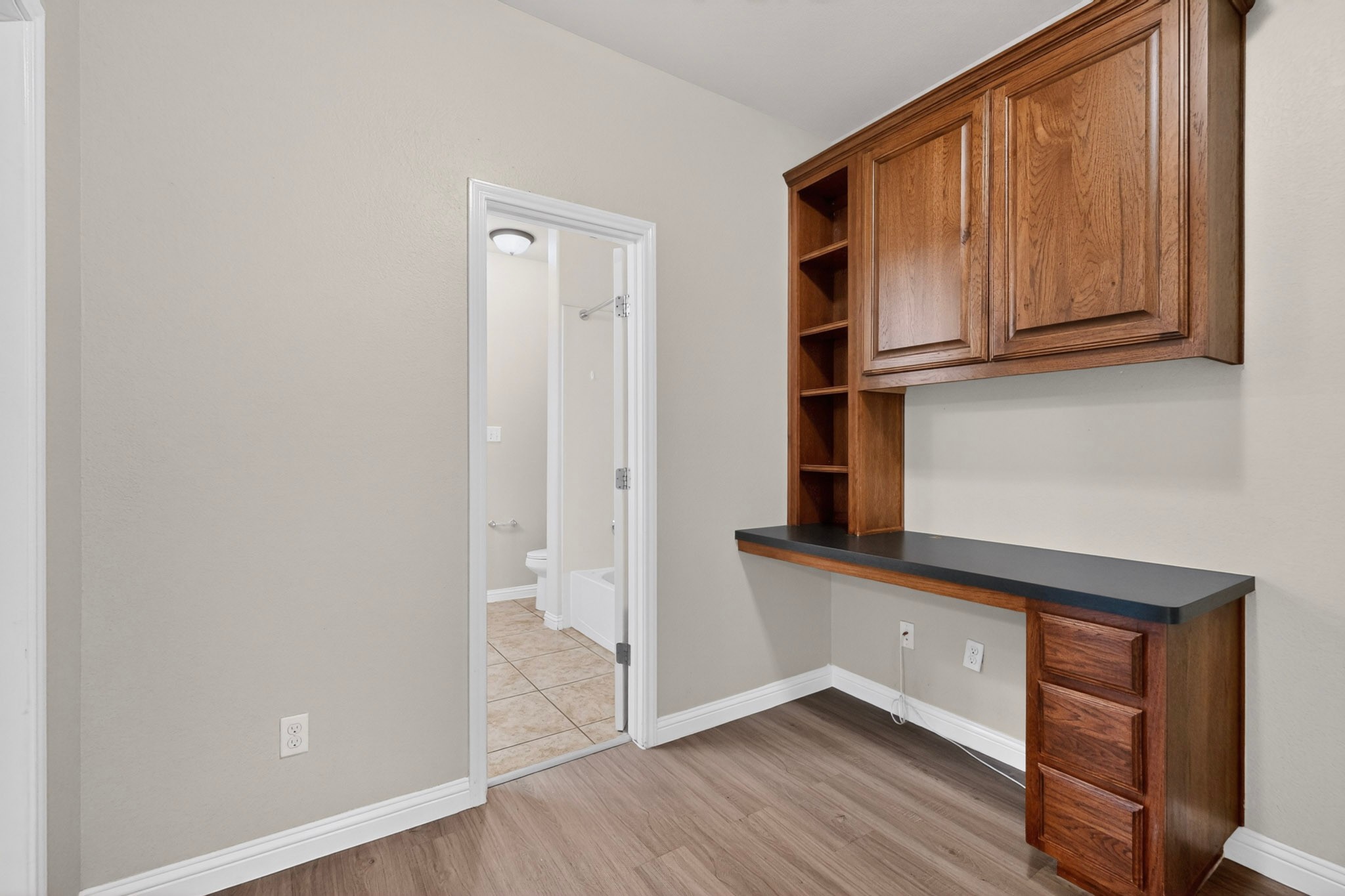 178 Limestone Trail Austin, TX 78737 - Photo 34 of 40 Built-in wood-finish desk with a dark countertop, integrated shelving, and upper cabinetry