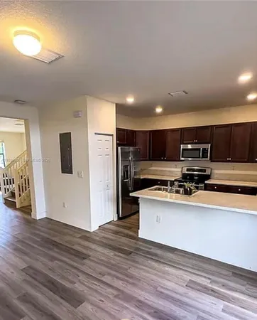 a view of kitchen with stainless steel appliances wooden floor and large window