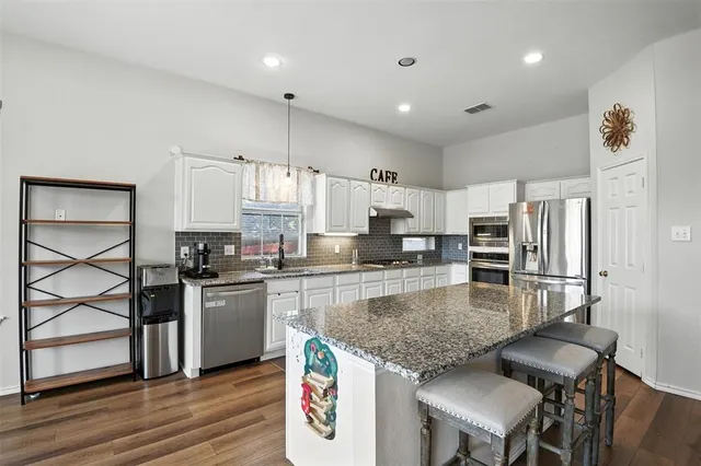 a kitchen with stainless steel appliances granite countertop a stove refrigerator sink and cabinets