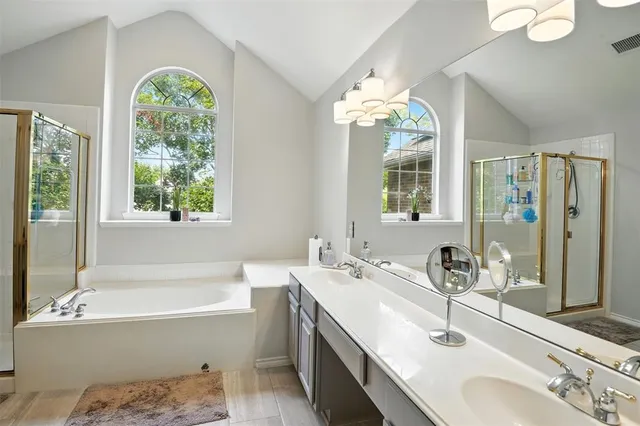 a bathroom with a double vanity sink bathtub and next to a window