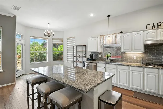 a kitchen with granite countertop kitchen island a table and chairs in it
