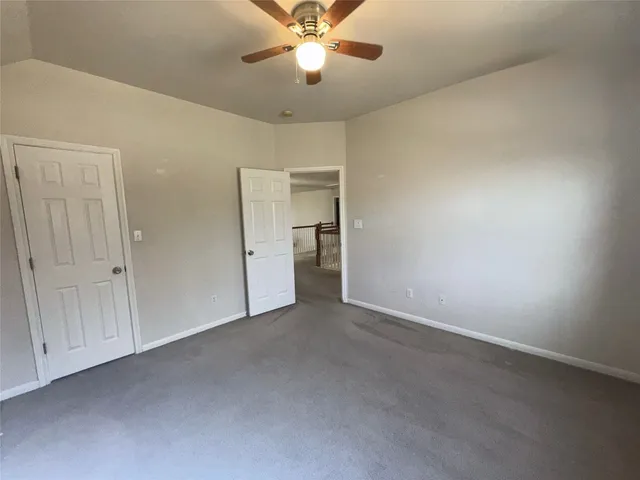 an empty room with closet and a ceiling fan