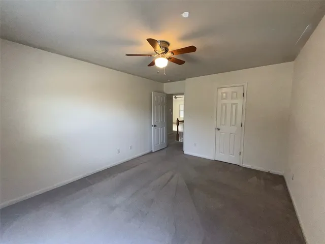 an empty room with closet and a ceiling fan