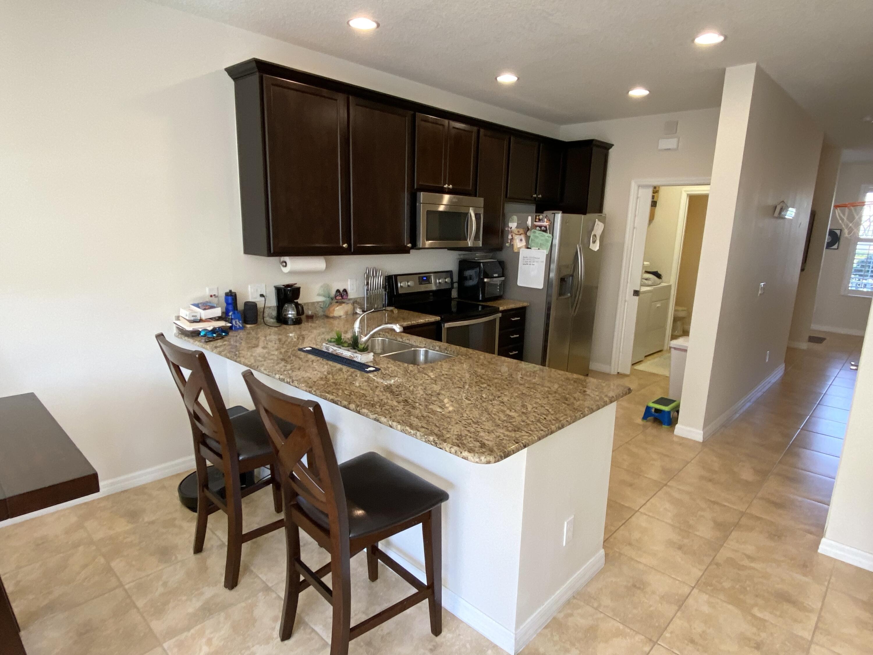 1370 Turnbridge Drive Jupiter, FL 33458 - Photo 4 of 12 a kitchen with stainless steel appliances granite countertop wooden cabinets a refrigerator and a sink