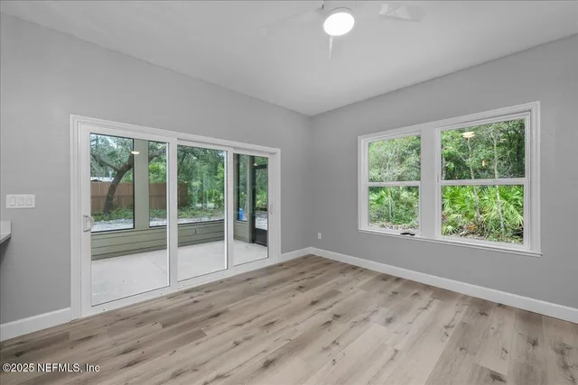 a view of empty room with wooden floor and fan