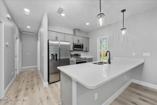 a kitchen with a sink a counter space appliances and cabinets