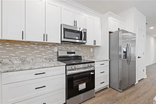 a kitchen with granite countertop cabinets stainless steel appliances and wooden floor