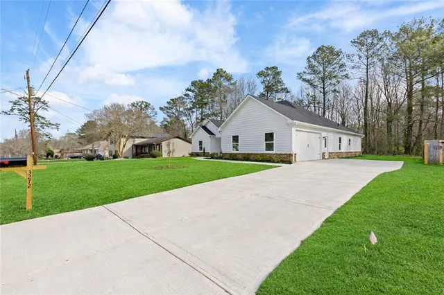 a view of a house with a yard and large tree