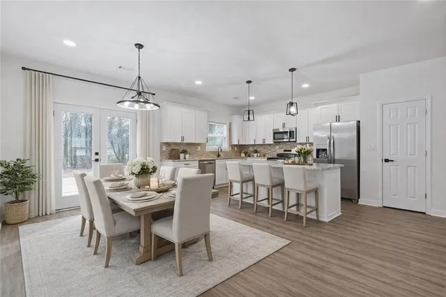 a view of a dining room and livingroom with furniture wooden floor a chandelier