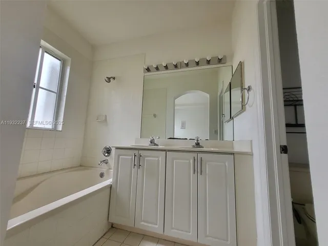 a bathroom with a granite countertop bathtub a sink and a window