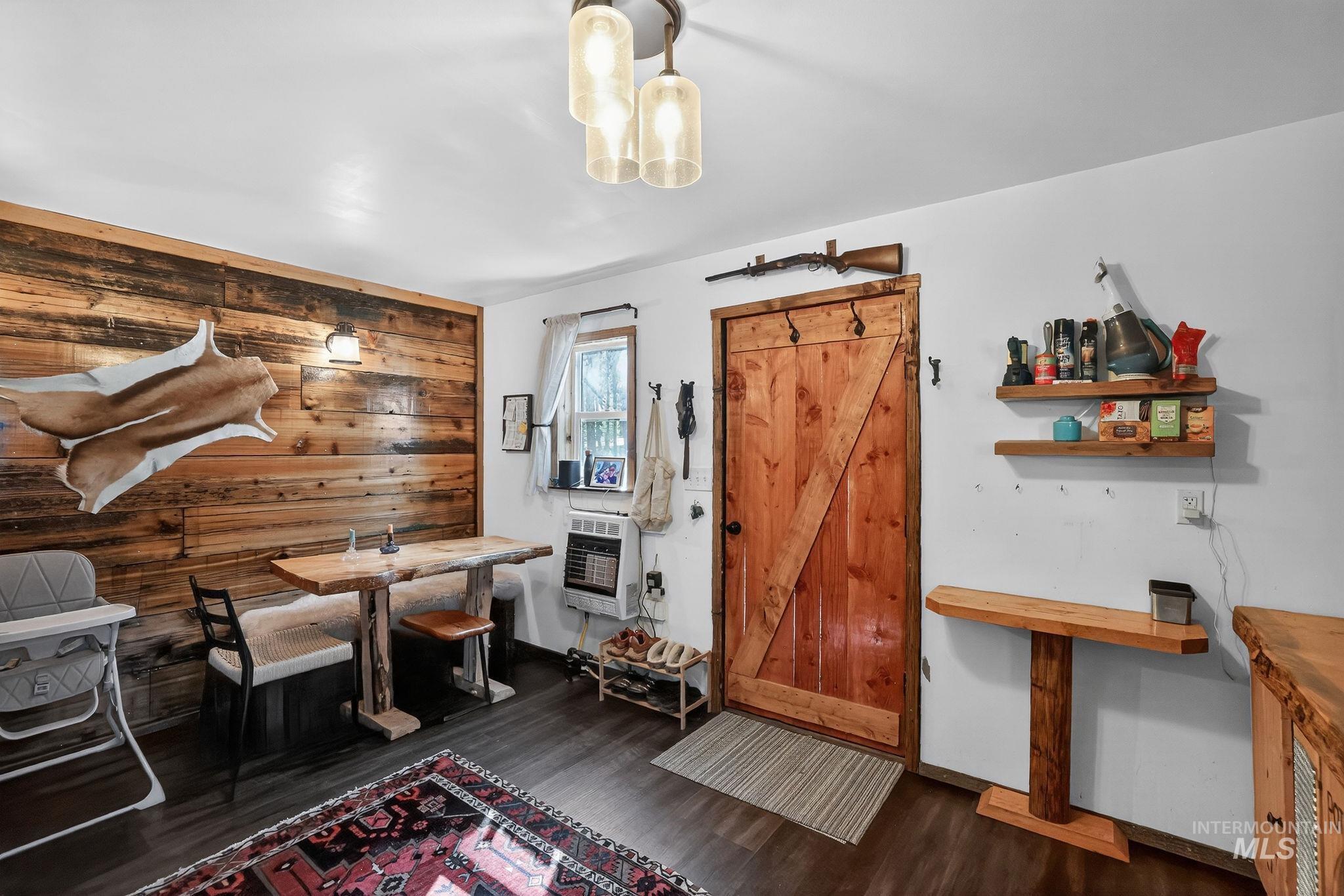 321 Secesh River Road McCall, ID 83638 - Photo 5 of 50 Interior space featuring wood-finish flooring, a rustic wood accent wall, a live-edge wooden table with built-in bench seating, a natural wood barn door, and a three-light ceiling fixture