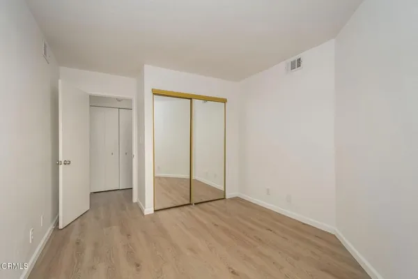 a view of an empty room with wooden floor and closet