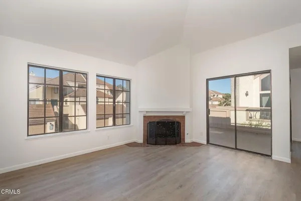 an empty room with wooden floor a fireplace and windows
