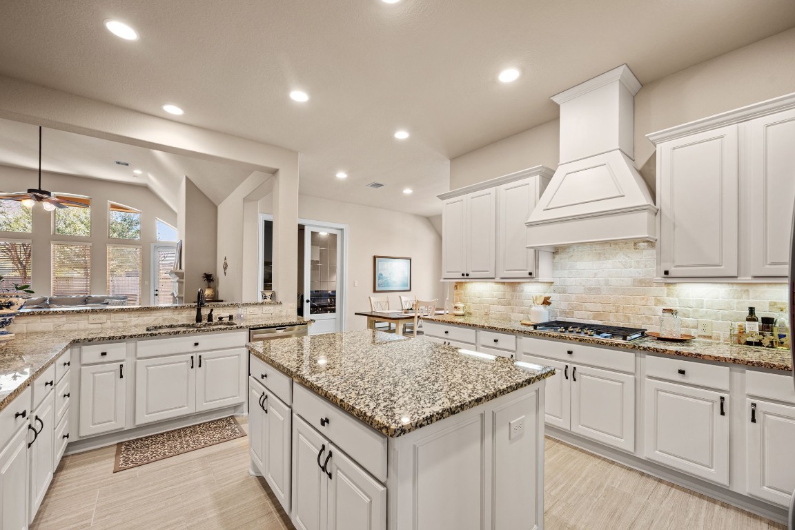 1607 Dove Ridge Drive Katy, TX 77493 - Photo 15 of 38 a kitchen with granite countertop kitchen island a sink stove and white cabinets