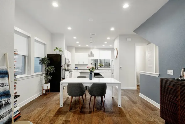 a kitchen with a dining table chairs refrigerator and microwave