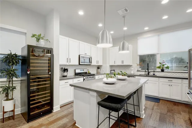 a kitchen with stainless steel appliances a stove a sink a refrigerator white cabinets and wooden floor