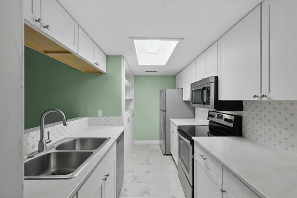 a kitchen with stainless steel appliances kitchen island a sink stove and refrigerator